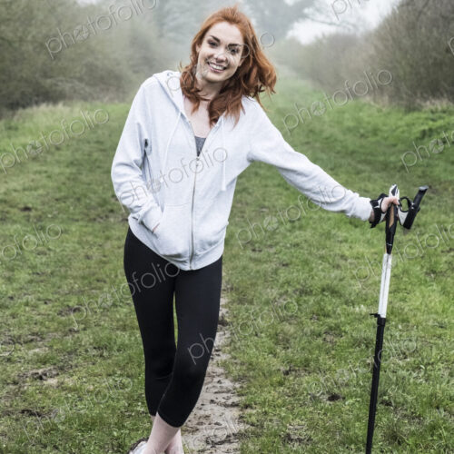 Young woman with long red hair wearing sportswear, exercising outdoors, looking at camera. Young woman with long red hair wearing sportswear, exercising outdoors, looking at camera.