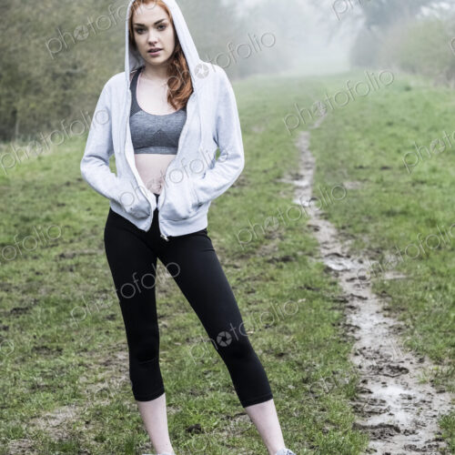Young woman with long red hair wearing sportswear, exercising outdoors, looking at camera. Young woman with long red hair wearing sportswear, exercising outdoors, looking at camera.