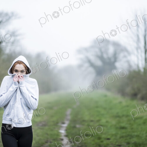 Young woman with long red hair wearing sportswear, exercising outdoors, looking at camera. Young woman with long red hair wearing sportswear, exercising outdoors, looking at camera.