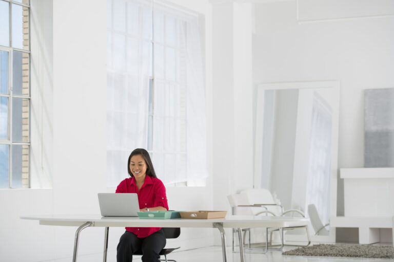 An office in the city. Light and airy working environment. A woman seated using a laptop.