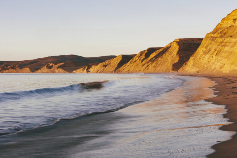 Steep cliffs and beach with surf at dawn
