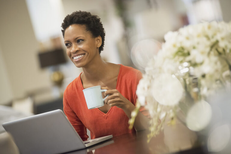 Woman relaxing at home with laptop and coffee