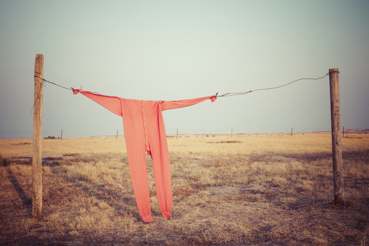Agriculture category — Bright red long johns hang from a wire clothesline between fence posts on a wide South… Bright red long johns hang from a wire clothesline between fence posts on a wide South…