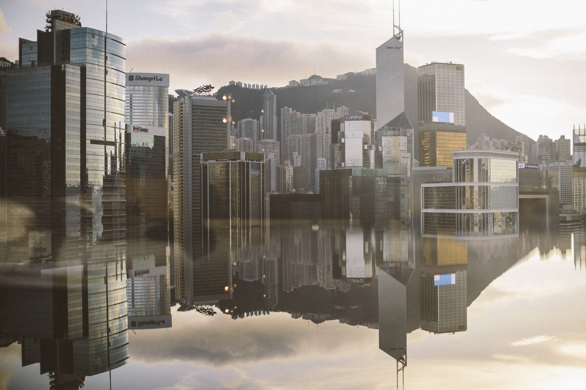 Cityscape with modern skyscrapers reflected in calm sea.