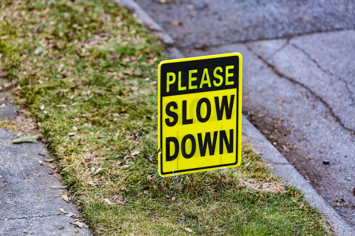 Editorial category — Please Slow Down sign on lawn between a sidewalk and the street Please Slow Down sign on lawn between a sidewalk and the street