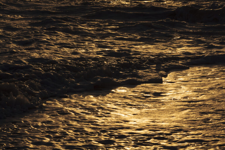 Breaking ocean waves, shadows and light reflections on the water surface.